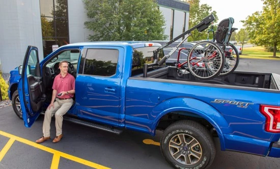 scooter loaded into the back of a blue pickup truck using an out rider scooter lift